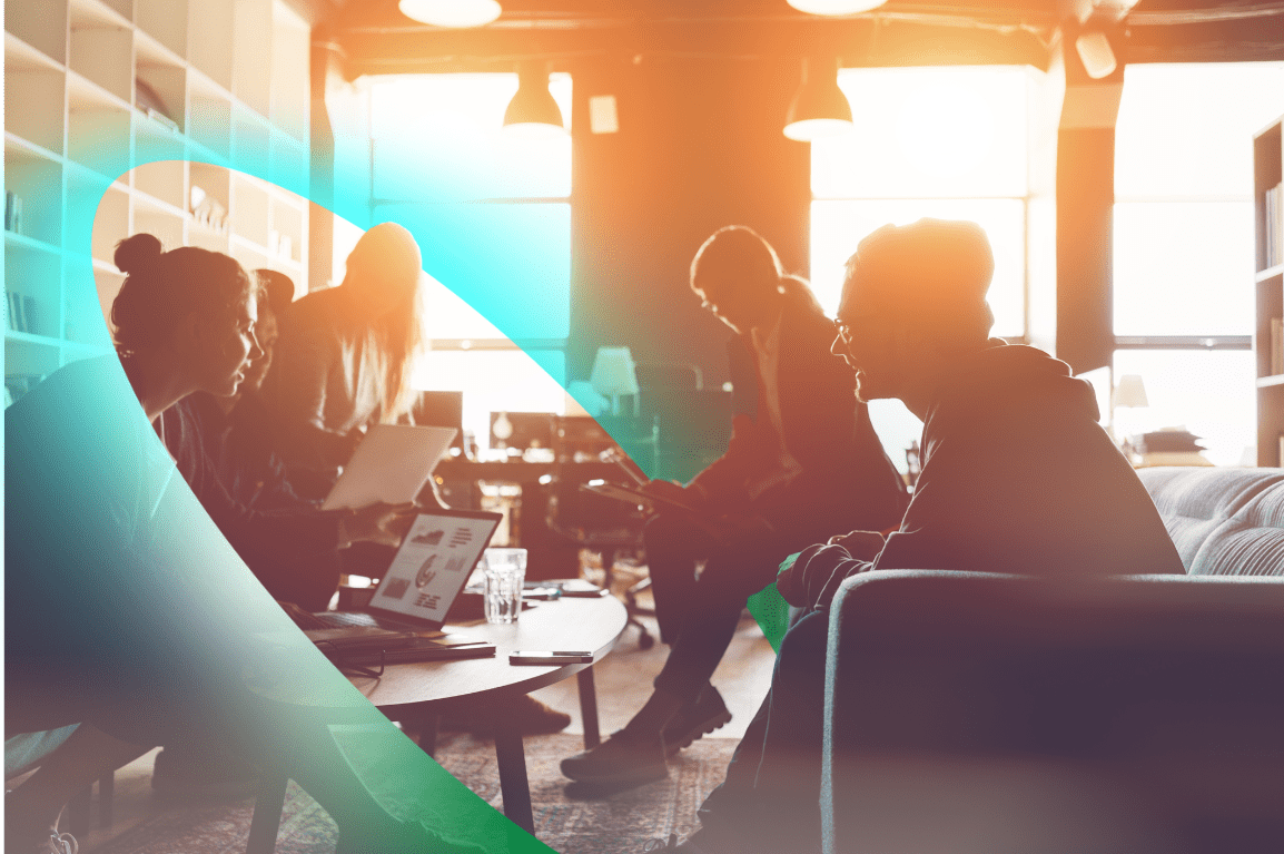 People sitting in an office space with the sun streaming in through a window behind them.