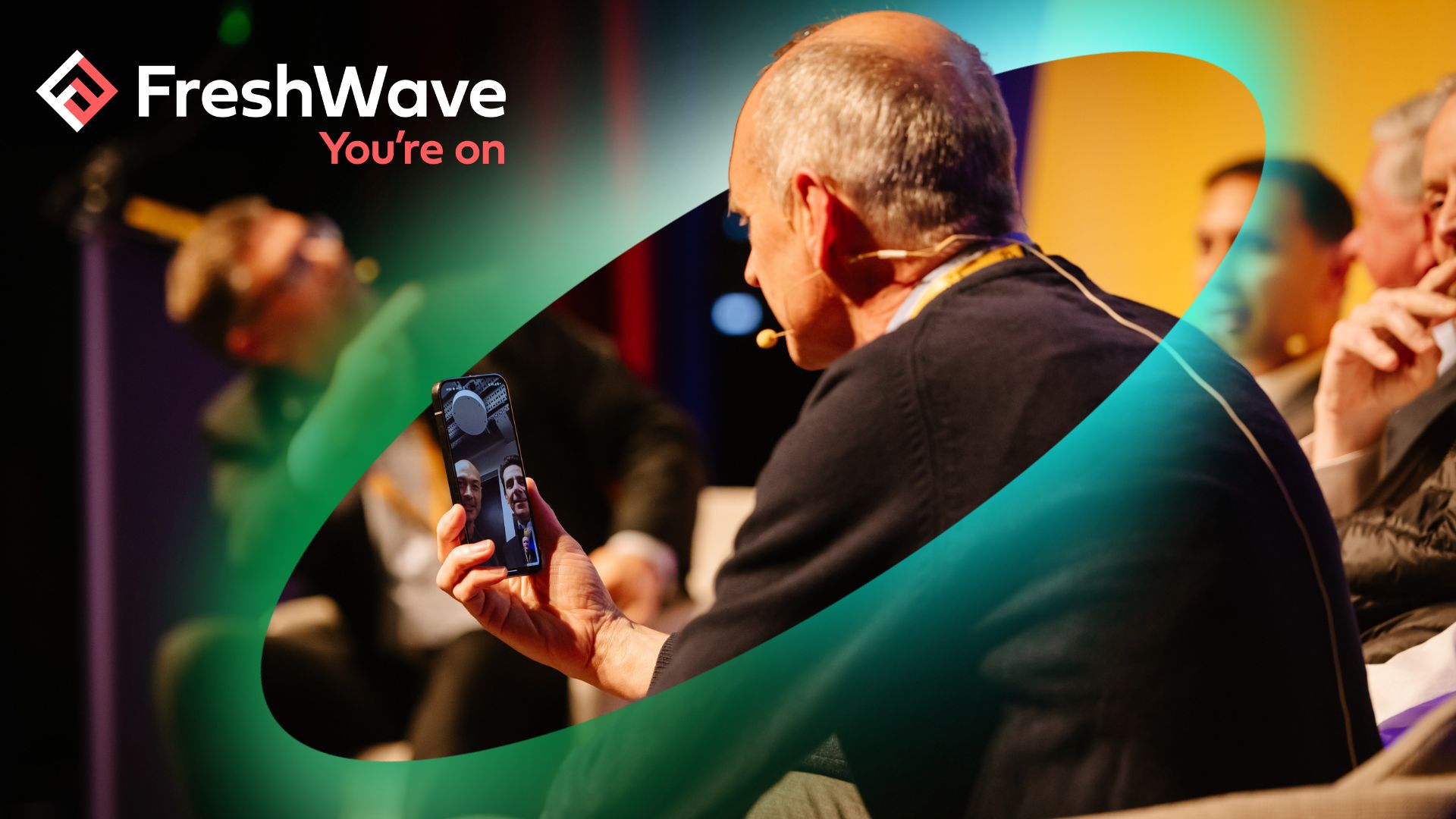 The back of a man while he participates in a video call. There is a green-blue ellipse surrounding him and the phone.
